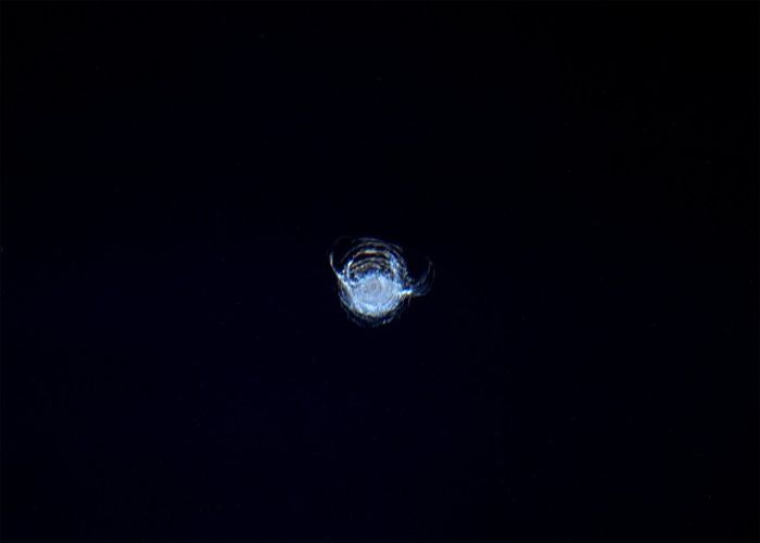 Скол на стекле иллюминатора МКС на фоне черного космоса (2 фото)