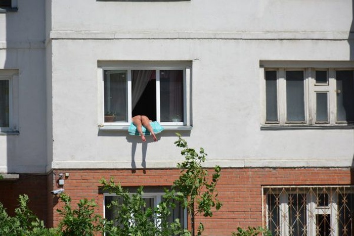 Жители Новосибирска жалуются на женщину, загорающую обнаженной на подоконнике своей квартиры (3 фото)