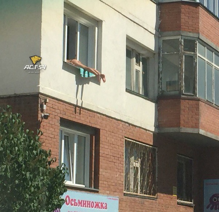 Жители Новосибирска жалуются на женщину, загорающую обнаженной на подоконнике своей квартиры (3 фото)