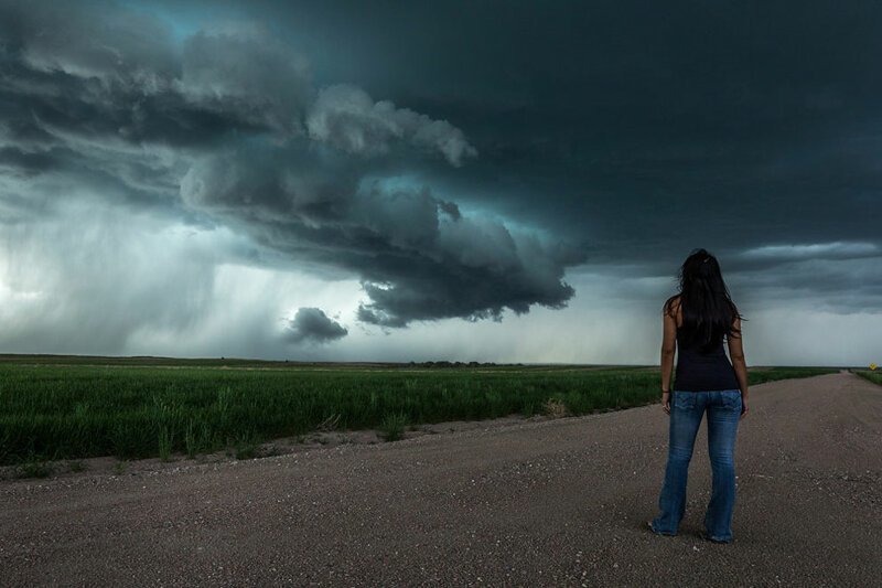 Женщину фотографируют на фоне торнадо