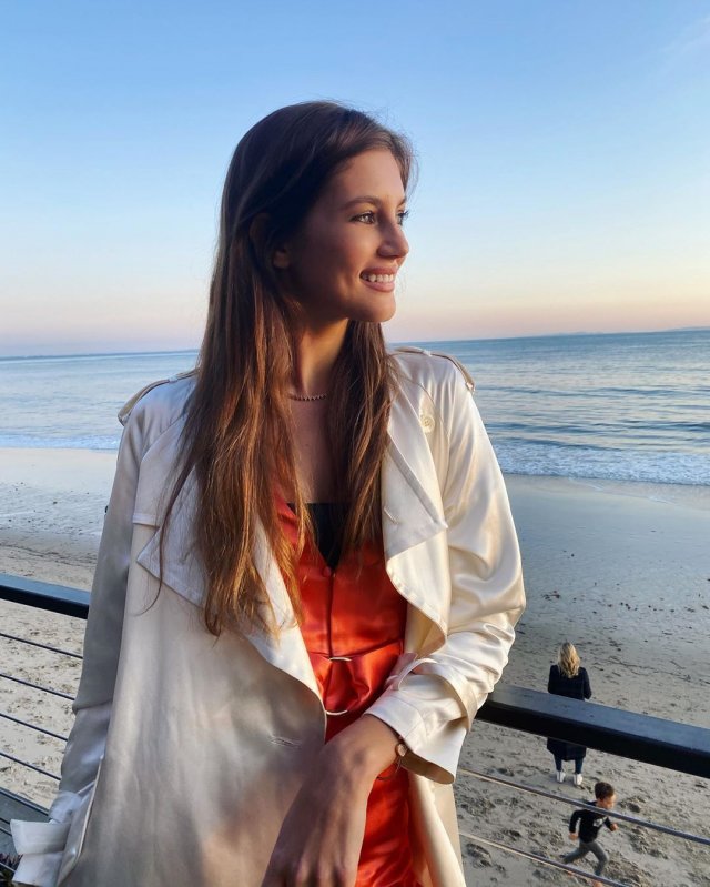 Валери Кауфман в оранжевом платье и белой куртке на берегу
