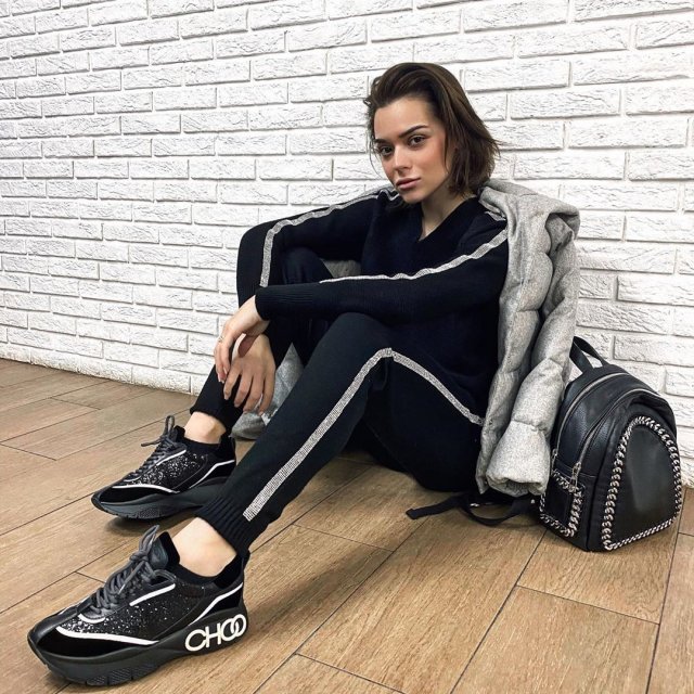 Аделина Сотникова в спортивной черной одежде сидит на полу прижавшись к стене