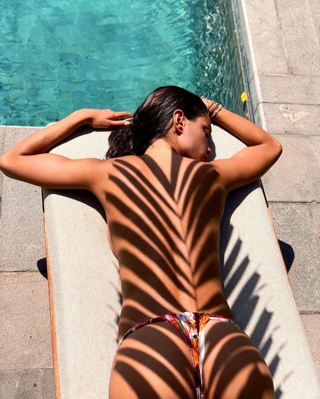 Джоана Санс под пальмой около бассейна