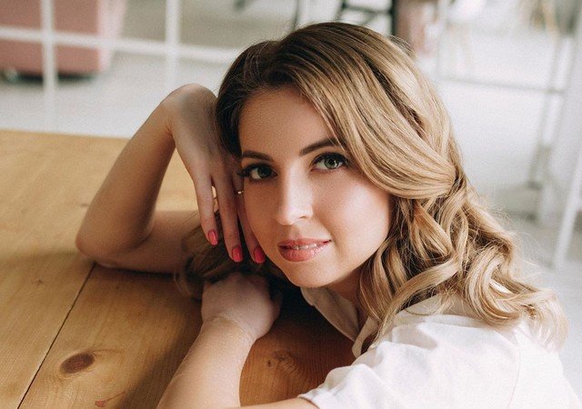 Екатерина Диденко в макияже сидит, облокотившись на стол