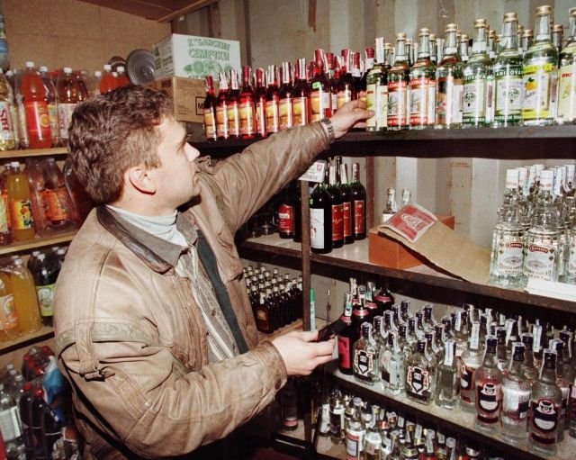 Налоговый инспектор осматривает бутылку водки