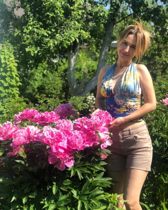 Элеонора Хабибулина на фоне цветов в шортах и кофте