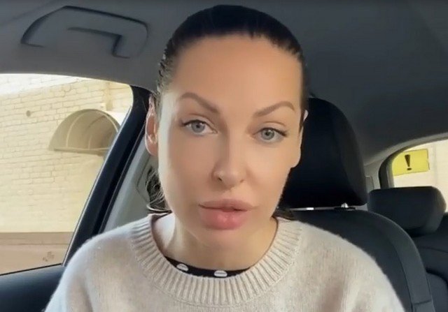 Наталья Краснова в белом свитере, рубашке сидит в машине
