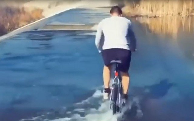 Мужчина едет по воде на велосипеде