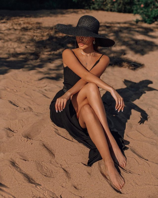 Стюардесса Алена Глухова в черном платье и шляпе на песке