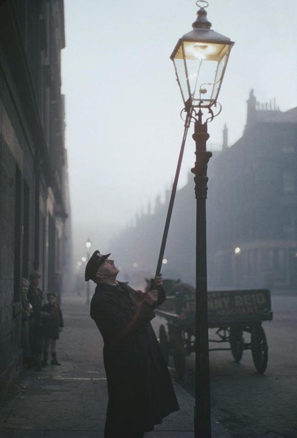 Фонарщик зажигает газовую лампу на улице в Глазго. Шотландия, 1955 год