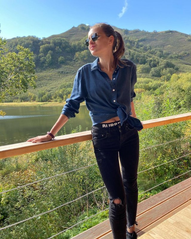 Блогер Ангелина Дубровская в рубашке и джинсах в горах