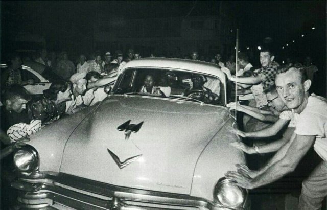 Толпа пытается перевернуть автомобиль с темнокожей семьей во время расовых беспорядков в г. Клинте, США. 1956