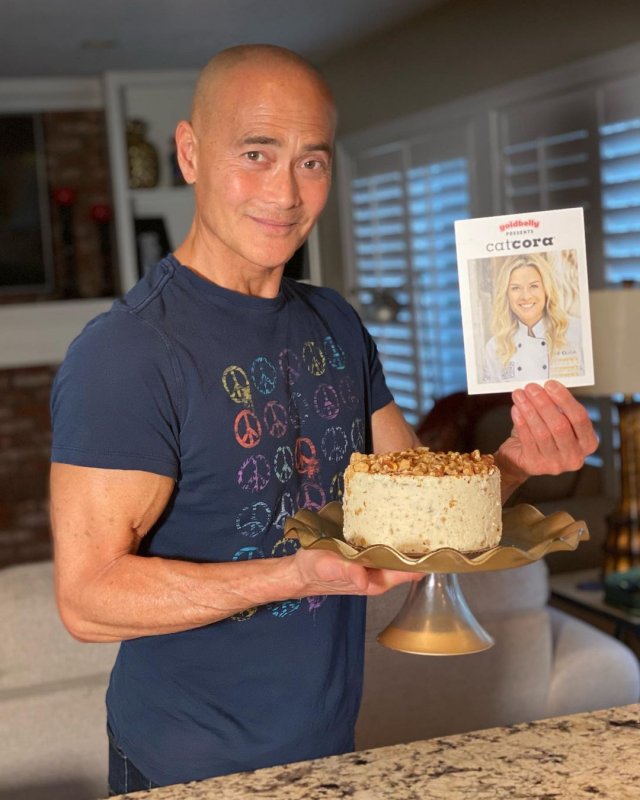 Марк Дакаскос в синей футболке с тортом и книгой