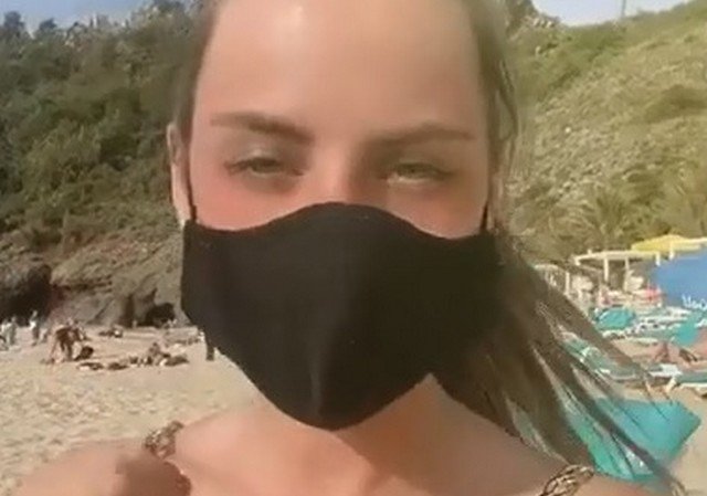 Девушка в маске загорает на пляже