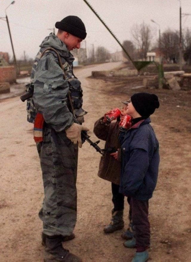Солдат федеральных сил угощает чеченских ребят кока-колой, 1996 год