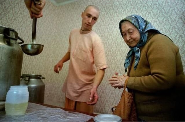 Пенсионерка получает еду в обмен на порцию песнопений в московском отделении секты Хара Кришны, 1993 год.