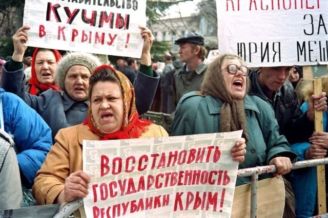 Крымчане держат плакаты и кричат перед крымским парламентом в Симферополе в знак протеста