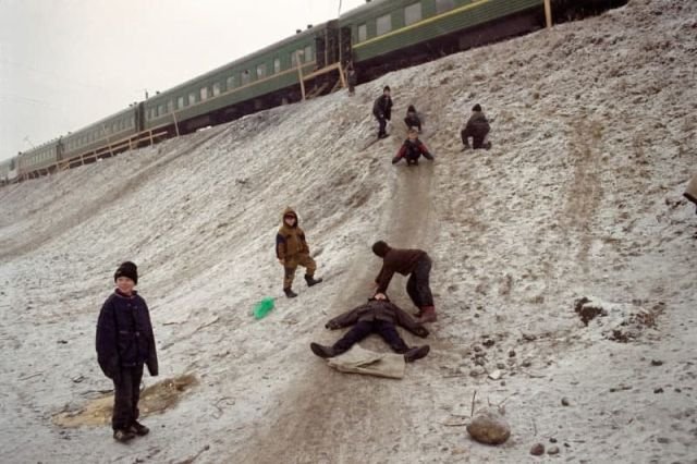 Дети катаются с горки рядом с путевой машинной станцией (Жилые вагоны). Россия, 1999 г.