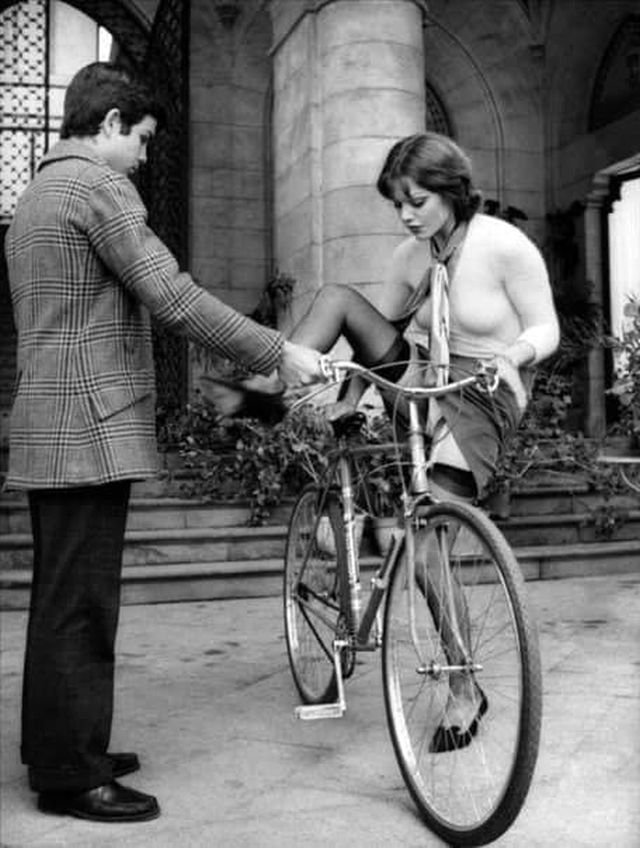 Молодой человек галантно помогает даме взобраться на велосипед. Италия, 1973 г.