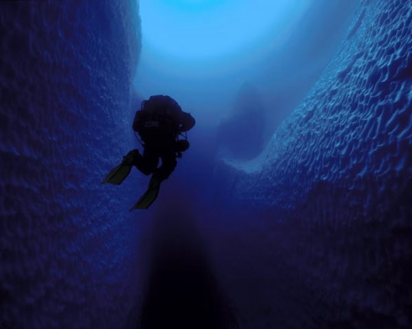 Дайвер исследует подводную часть айсберга