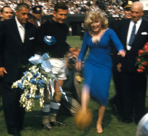 Мэрилин Монро в качестве почетной гостьи ударяет по мячу, чтобы начать футбольный матч, 1957