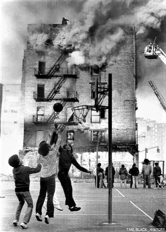 Дети играют в баскетбол на фоне горящего здания, Гарлем, Нью-Йорк, 1975 год.