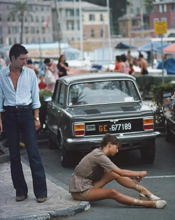 Девушка завязывает сандалии на тротуаре в порту Портофино, август 1977 года