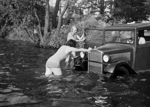 Женщины в купальниках пытаются вытолкнуть затонувший автомобиль BMW из воды. Германия, 1934 год.