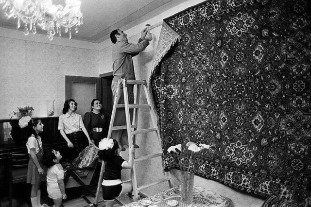 Глава семьи под восторженными взглядами своих родных прибивает к стене роскошный ковёр. СССР. 1970-е.