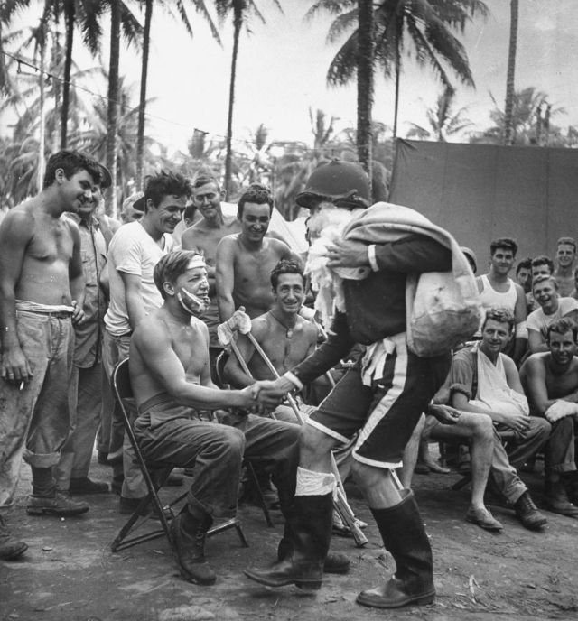 Санта-Клаус вручает подарки раненым американским солдатам на Гуадалканале в Рождество, 25 декабря 1943 года. Санта-Клаус вручает подарки раненым американским солдатам на Гуадалканале в Рождество, 25 декабря 1943 года.