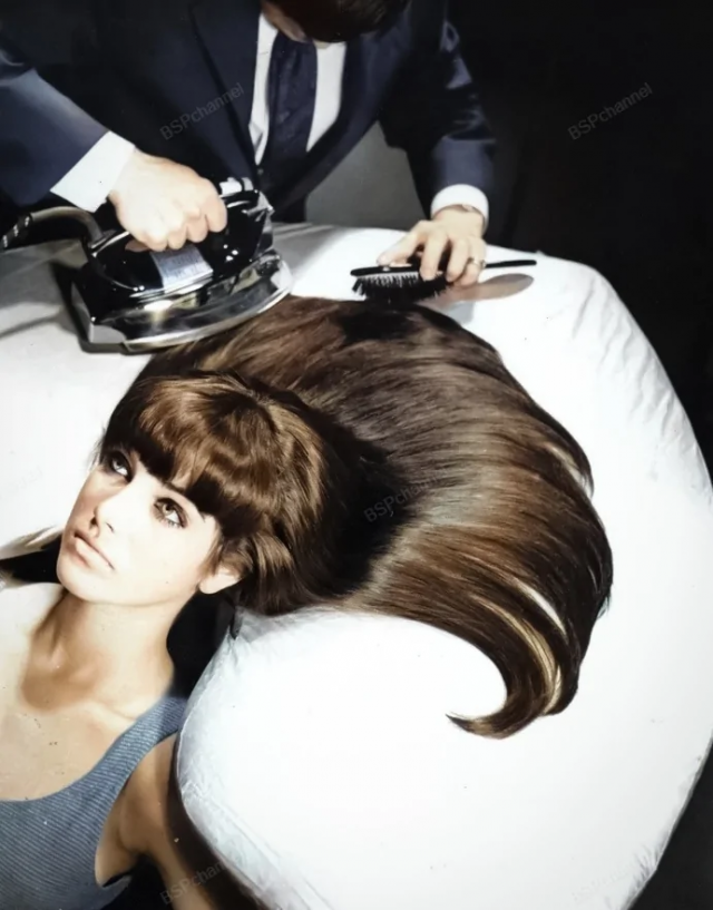 Парикмахер расчесывает и гладит волосы модели на доске, предназначенной для глажки волос. Нью-Йорк, 1965 год.