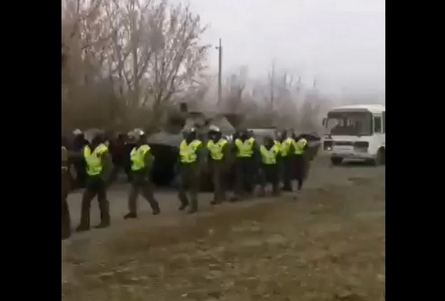 Солдаты идут по полю на фоне автобуса