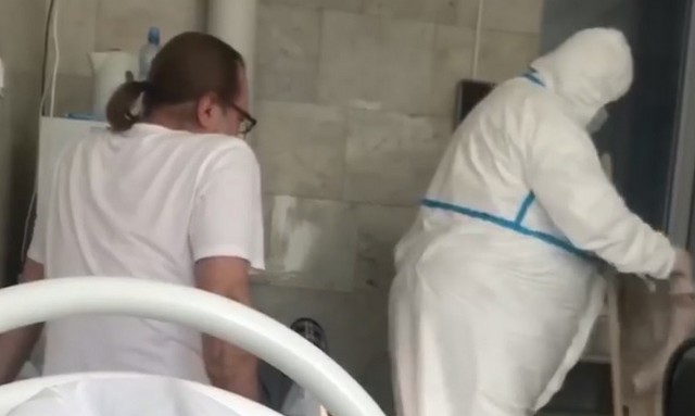 Мужчина в больнице смотрит на человека в защитной форме от коронавируса