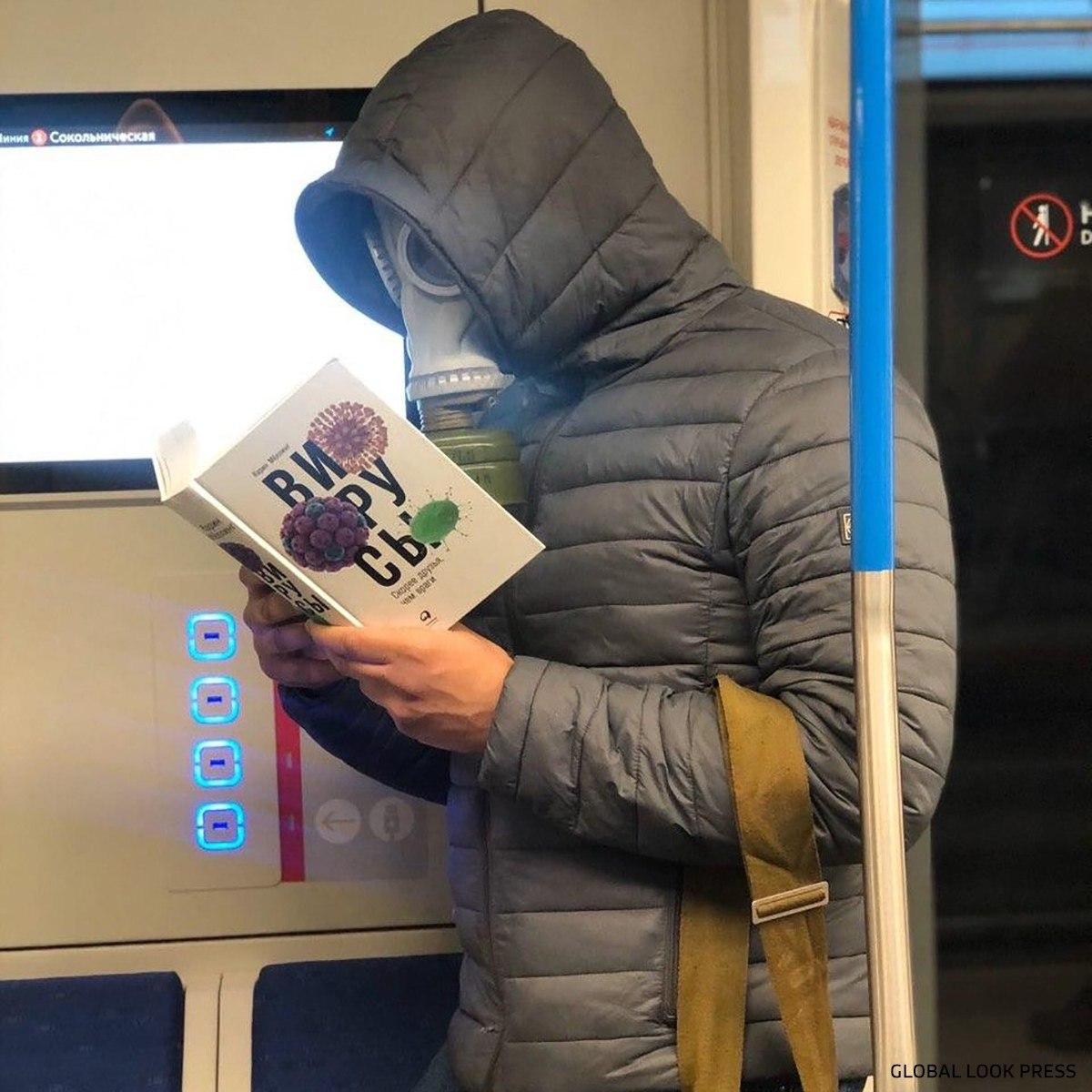 Мужчина в метро в противогазе и с книгой