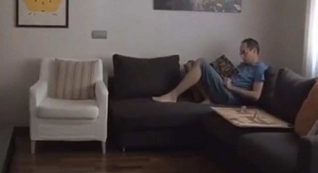 Мужчина сидит на коричневом диване и читает