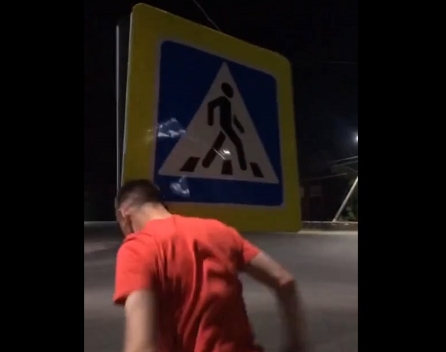 пьяный парень бьет головой дорожный знак