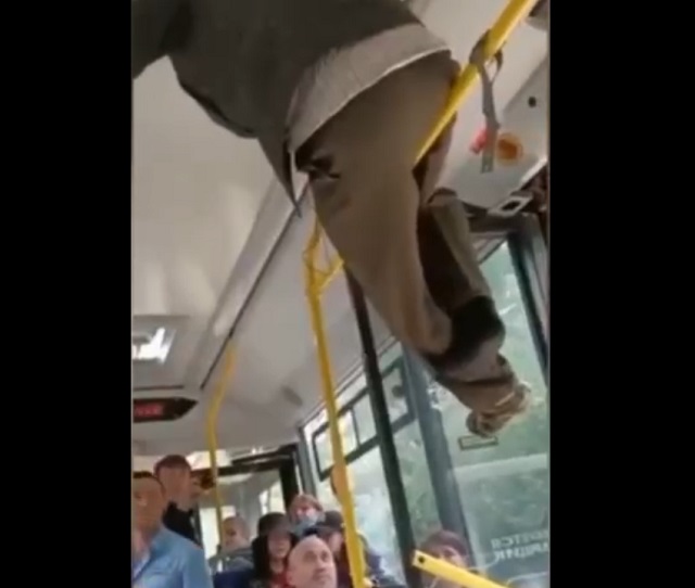 парень залез на верхний поручень в автобусе